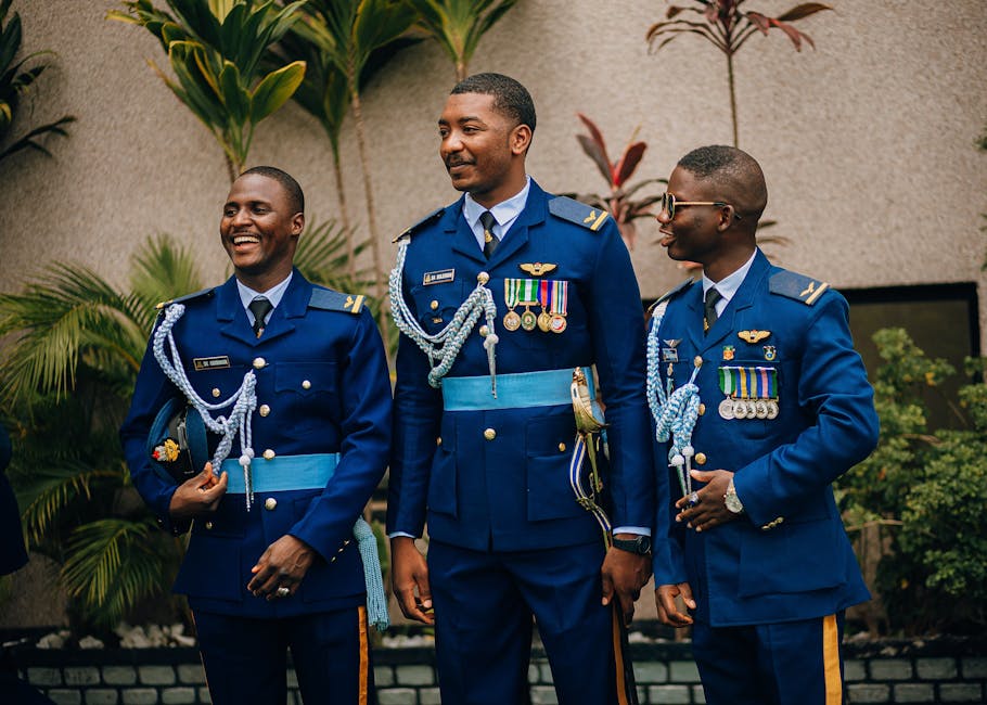 Three military officers in dress uniform adorned with medals, standing outdoors and smiling.