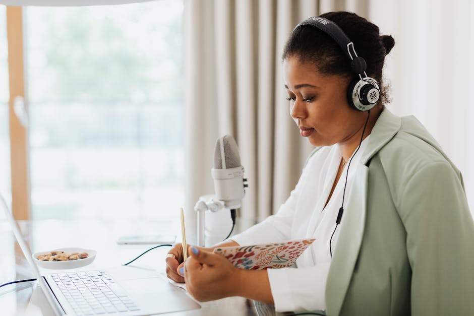 A focused woman recording a podcast indoors with headphones and microphone.