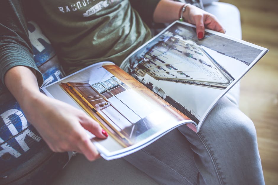 A person relaxes on a sofa, flipping through an architecture-themed magazine.